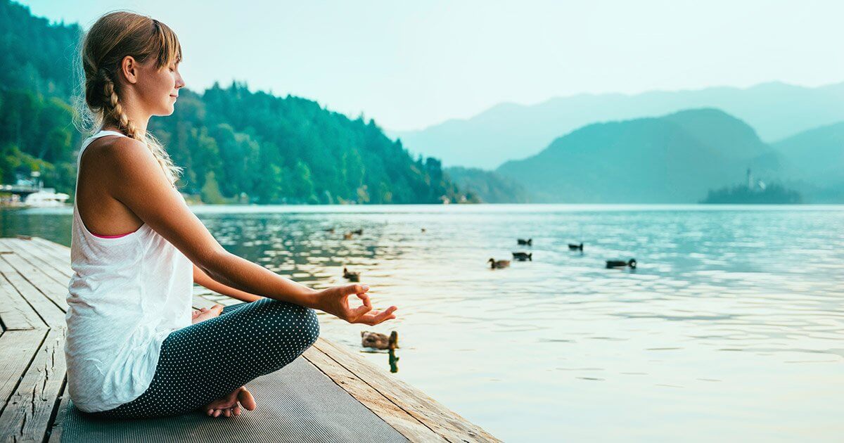 woman meditating by water